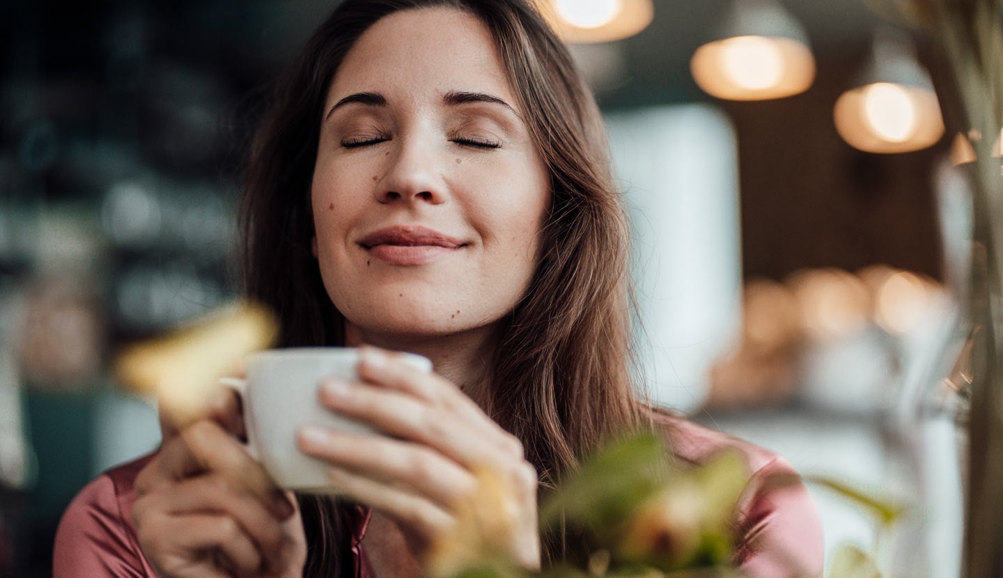 Mujer sosteniendo una taza con los ojos cerrados