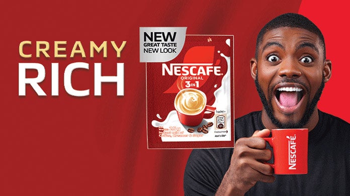 An excited man in a black shirt, holding a red NESCAFÉ mug