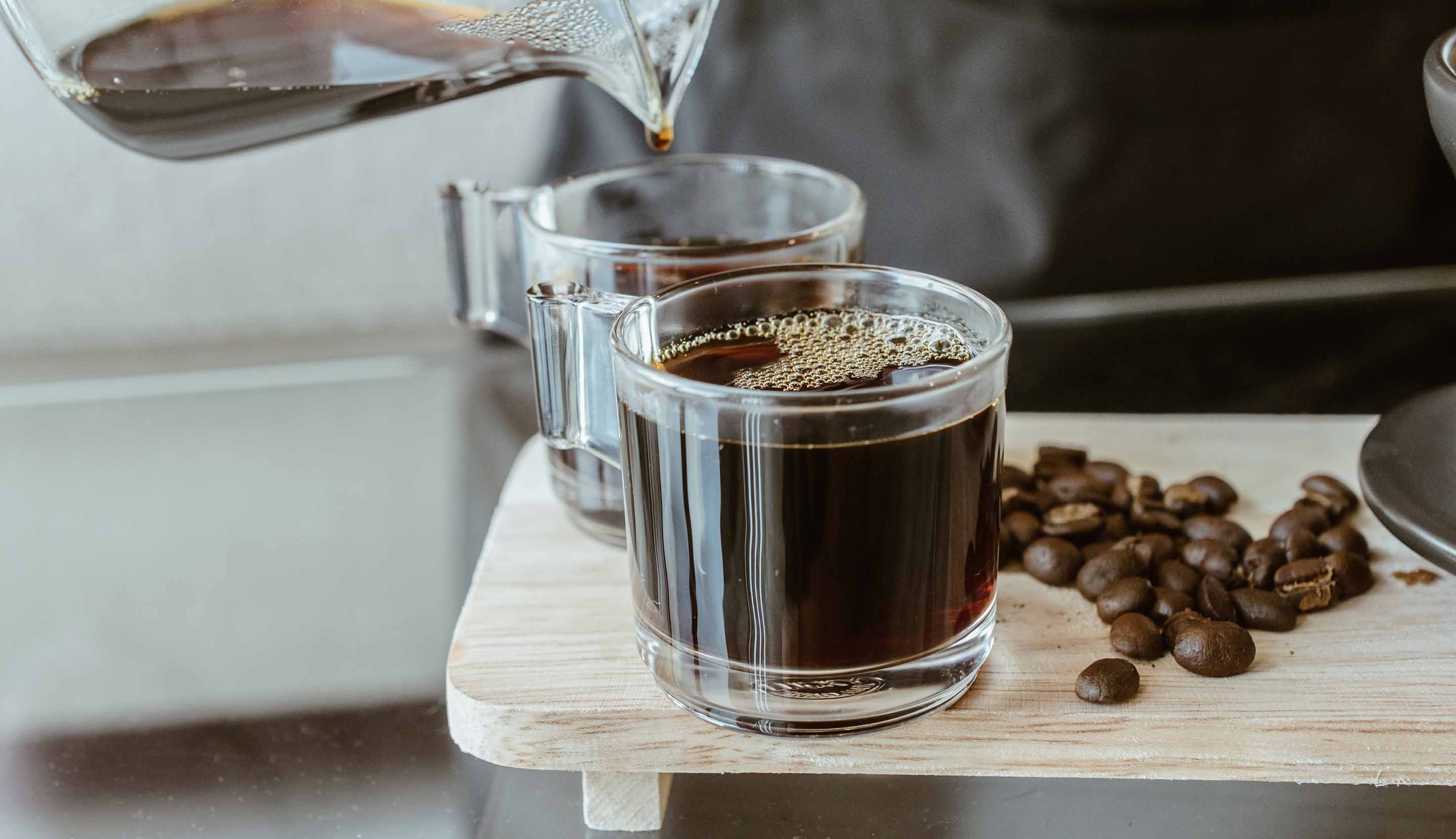 A top down shot of two coffees next to coffee beans