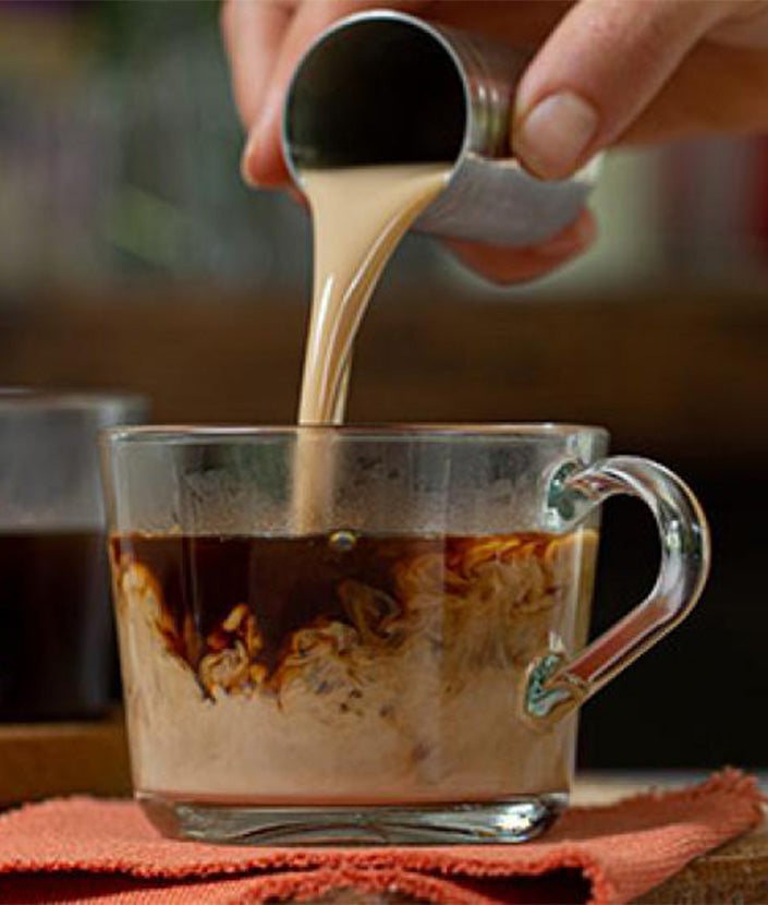 pouring baileys liquor into coffee