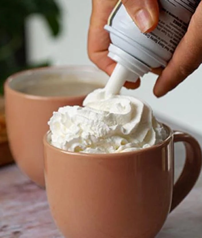 adding whipped cream onto cup