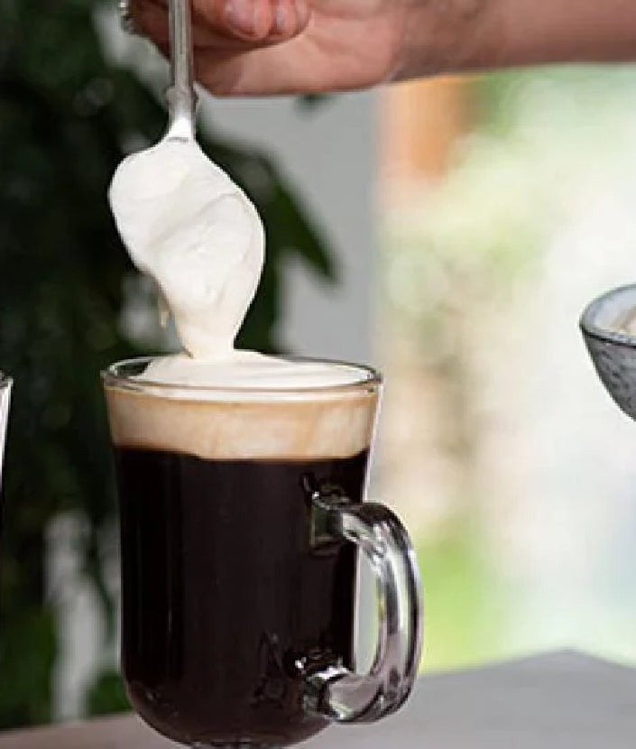 spoon adding whipped cream onto coffee