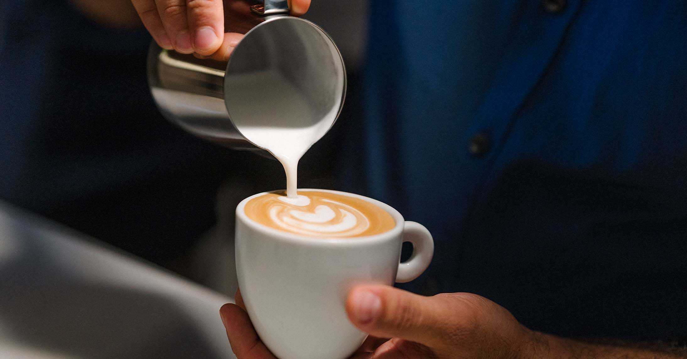 barista adding milk to coffee